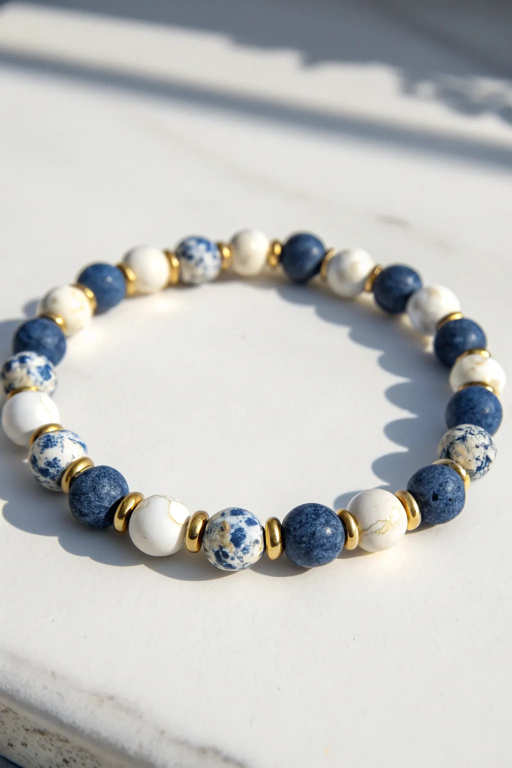 Blue and white clay bead bracelet with sprinkled metallic spacers for a clean, radiant finish.