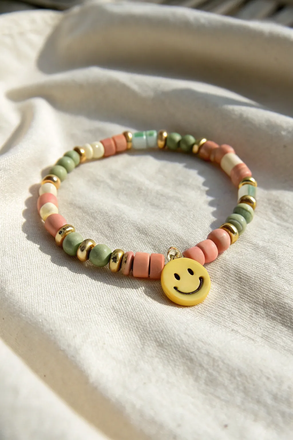 Bright smiley accent bracelet with pastel heishi beads, minimal styling, handmade charm.