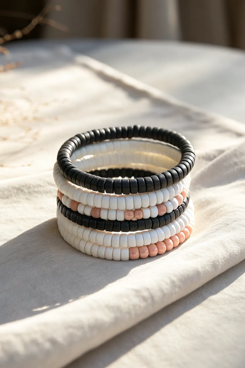 High-contrast black-and-white heishi bracelet stack with one soft accent bead, clean and chic.