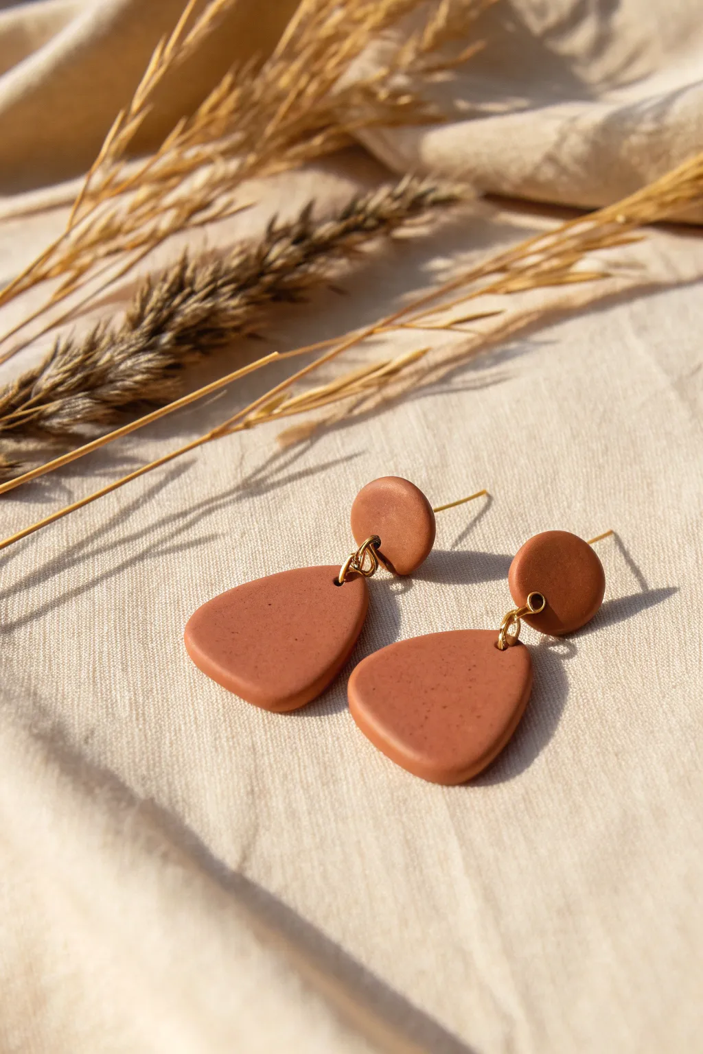 Abstract organic blob clay earrings in earthy terracotta with minimalist gold connectors.