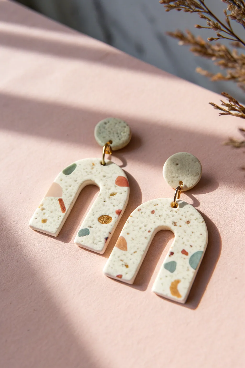 Beginner-friendly terrazzo clay earrings in simple arch shape, styled in soft pastel tones.