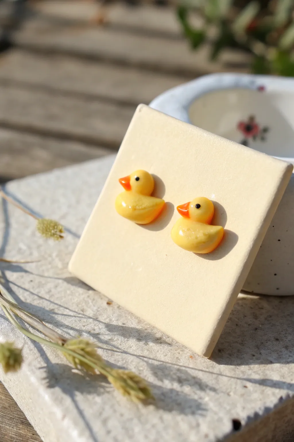 Tiny glossy duck stud earrings, minimalist and sweet, styled on a clean neutral display.