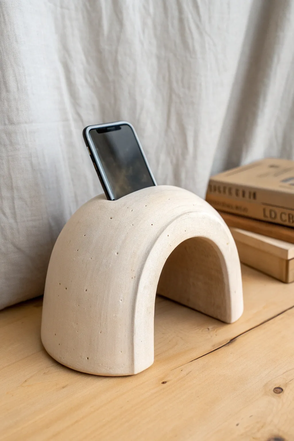 Minimal arch clay sound tunnel speaker with phone slot, styled in soft Scandinavian boho tones