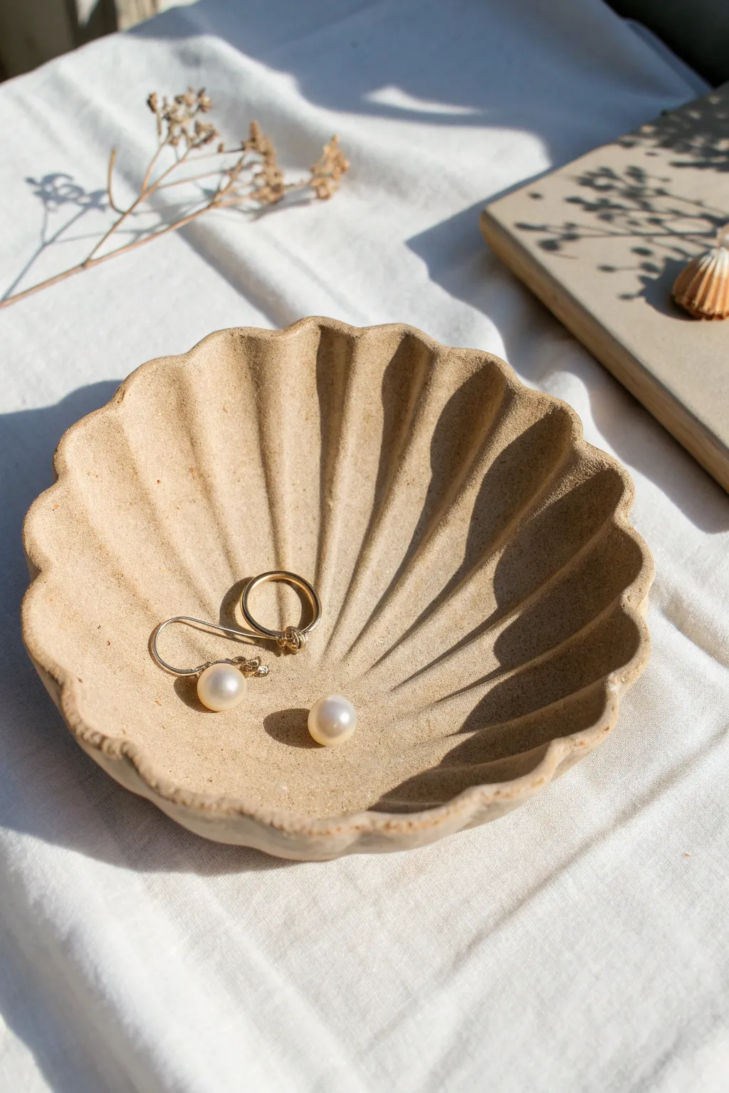 Shell-shaped clay tray in sandy tones, perfect for holding tiny treasures with beachy calm.