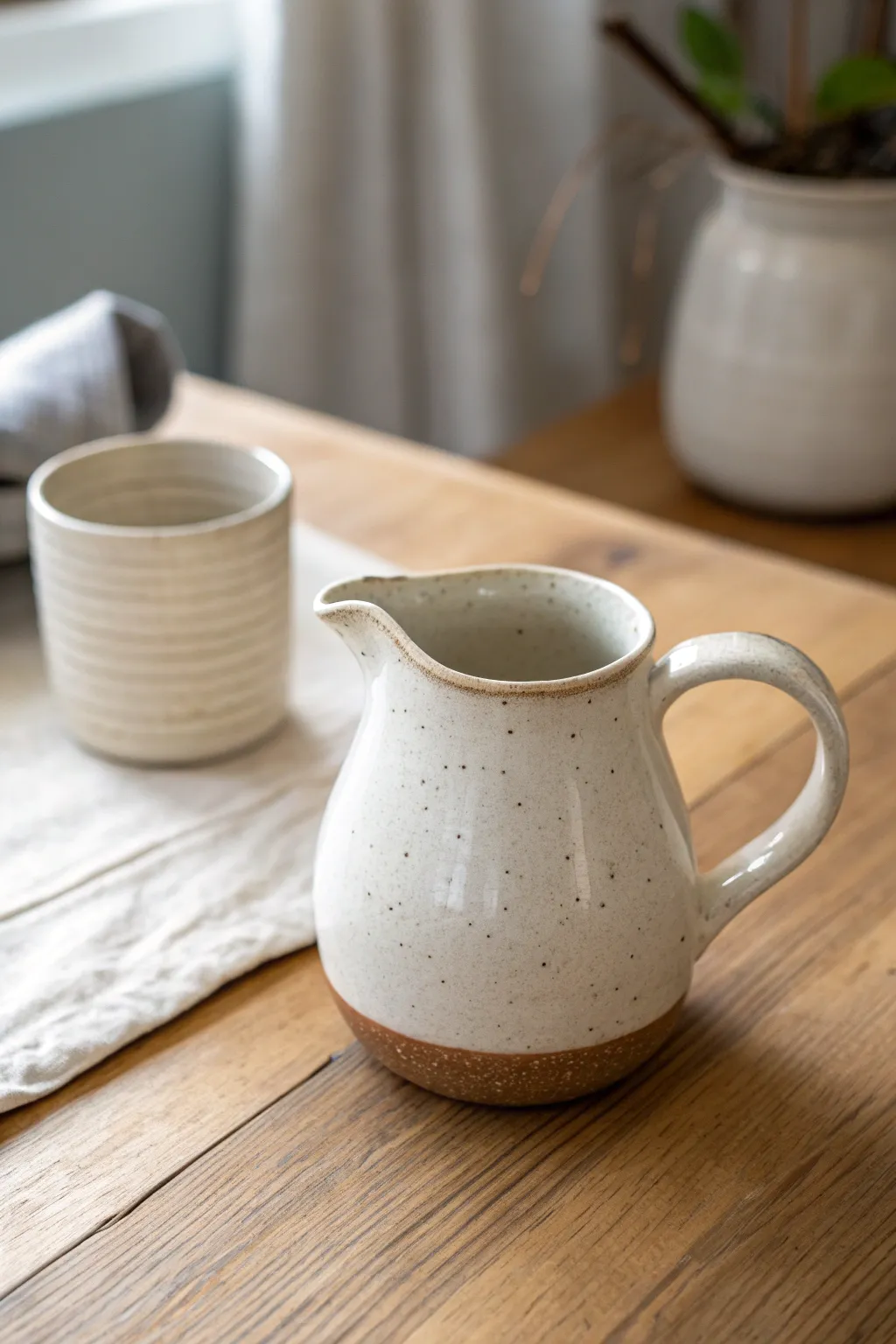 Wheel-thrown mini creamer with a clean spout and petite handle, styled in soft Nordic tones