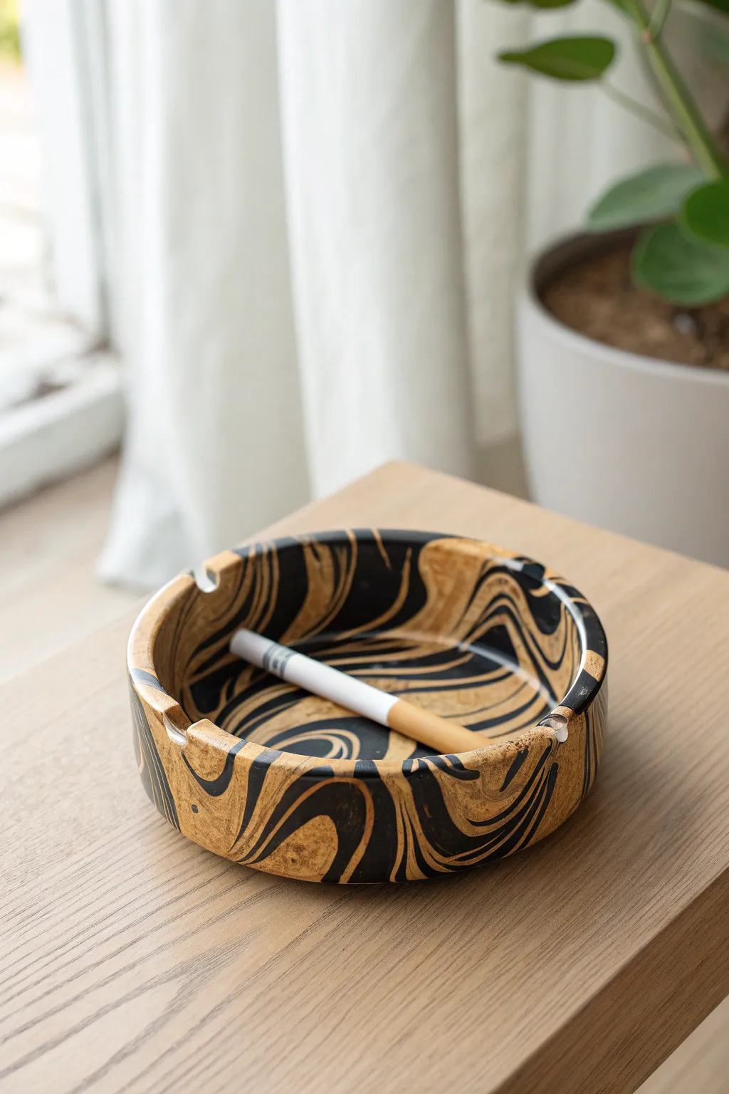 High-contrast black and cream marbled polymer clay ashtray in clean, sunlit minimalist style
