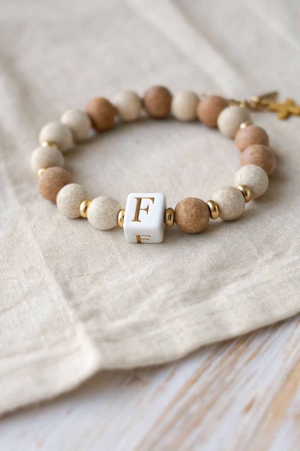 Cream clay bead bracelet with gold accents and a simple faith initial for a soft country look