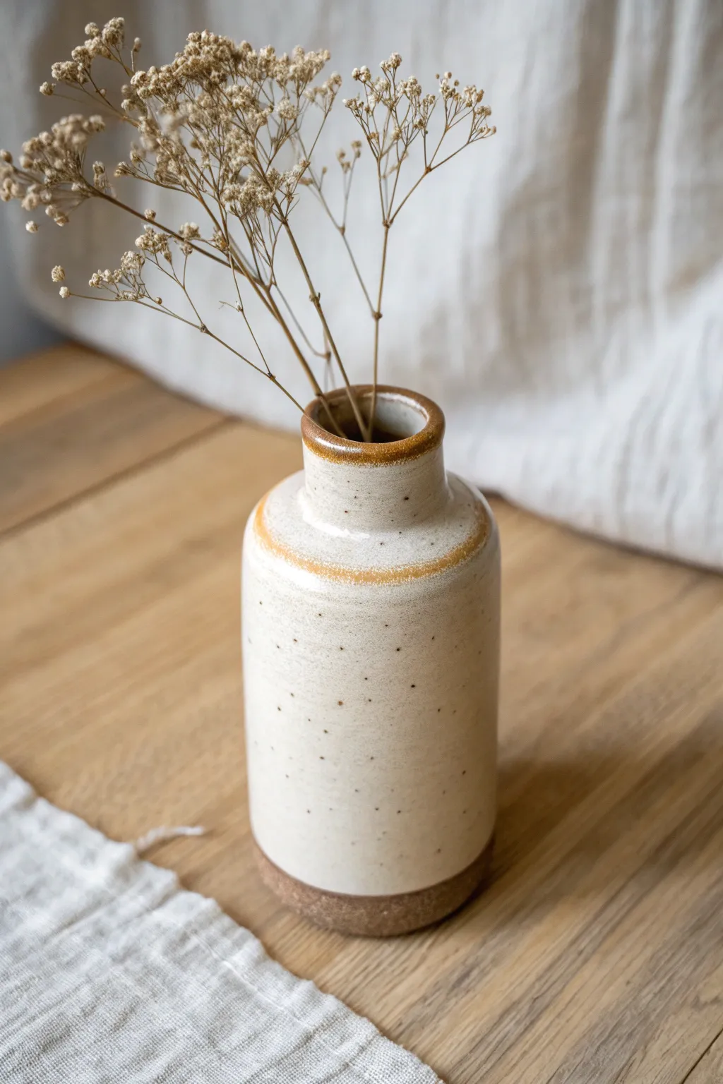 Minimal slab-built mini bud vase in a warm neutral glaze, styled with one airy dried sprig
