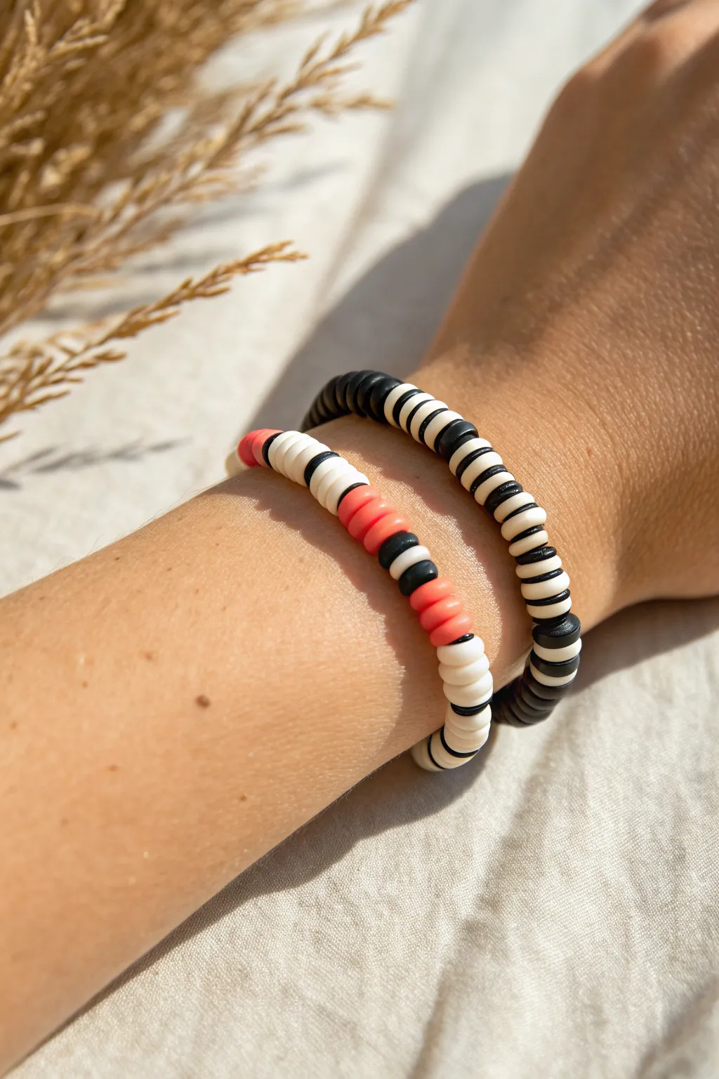 Black and white clay heishi bracelet with a tiny coral pop, minimalist and easy to wear.
