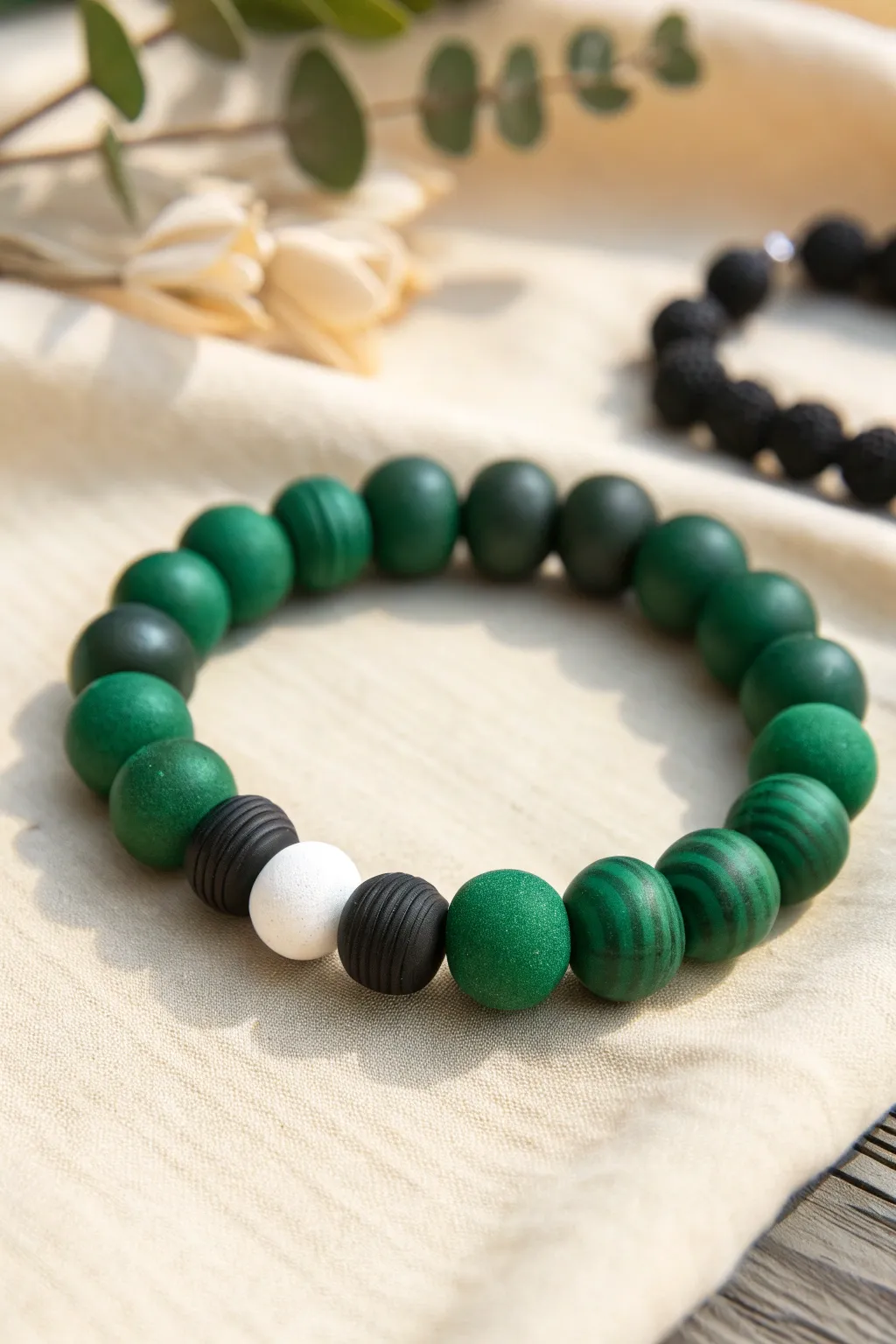 High-contrast hunter green and black striped clay bead bracelet with a tiny white break accent