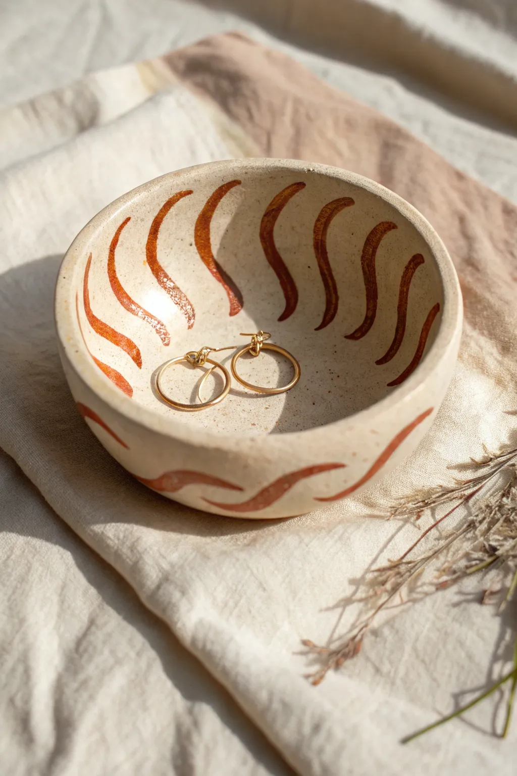 Minimal pinch pot bowl with wavy stripes, styled as a sweet catchall for earrings and pins.