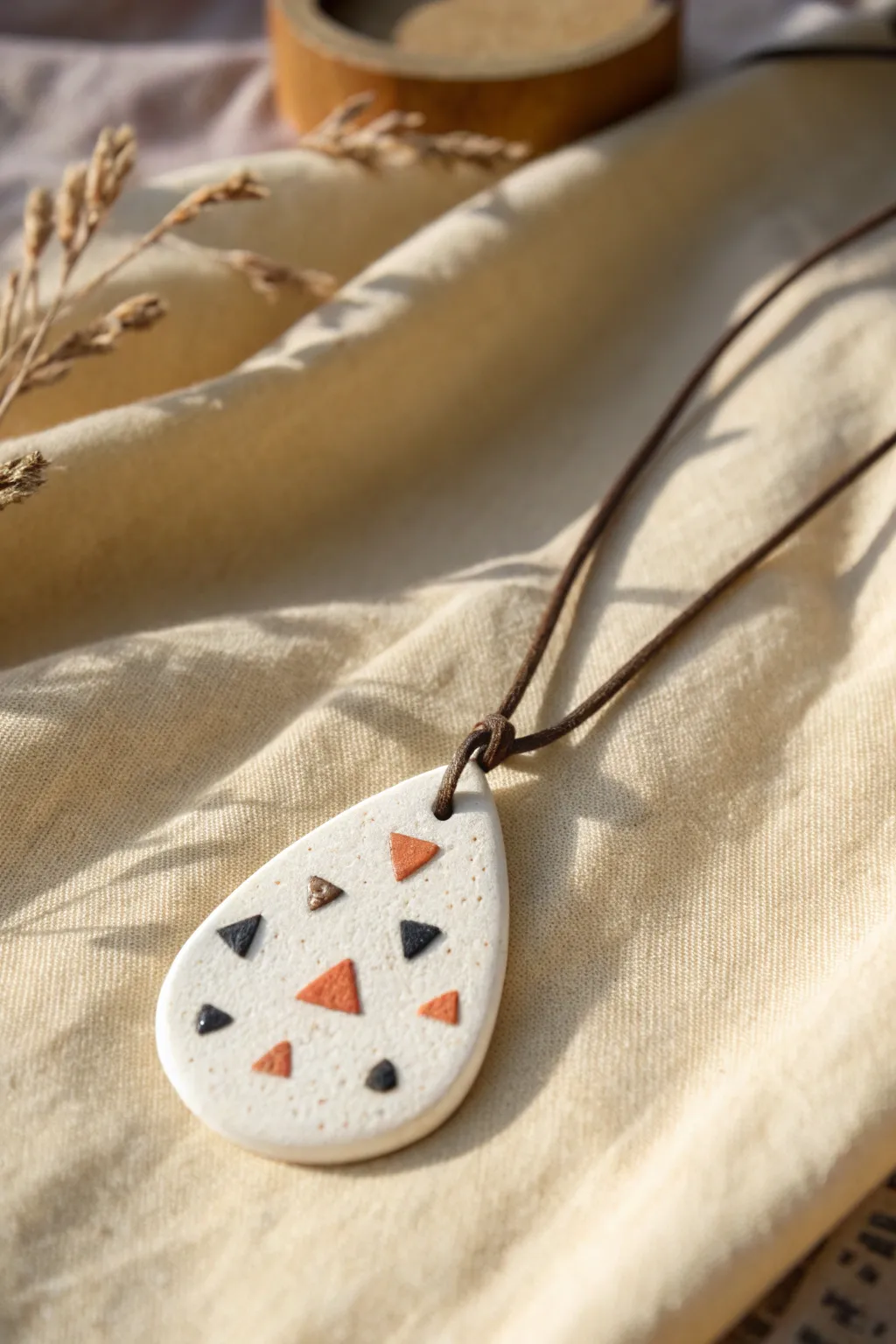 Minimal polymer clay pendant with tiny inlaid shapes, Scandinavian calm with a boho touch.
