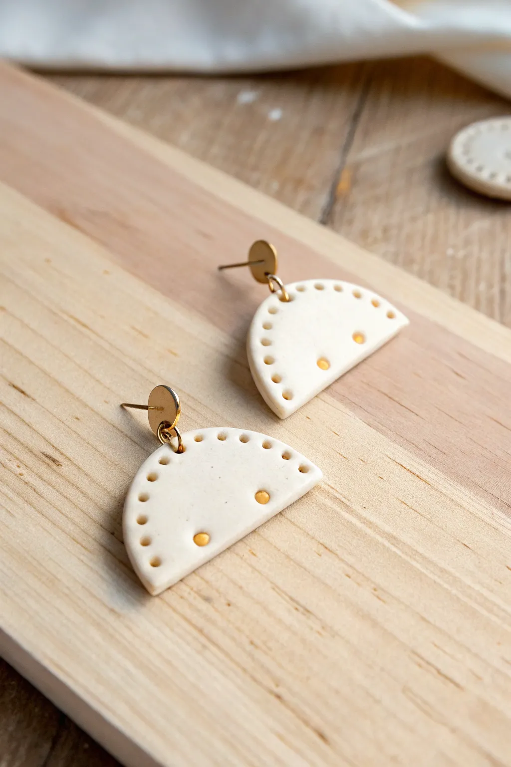 Minimal half-moon polymer clay earrings with tiny dot accents on light wood, soft and modern.
