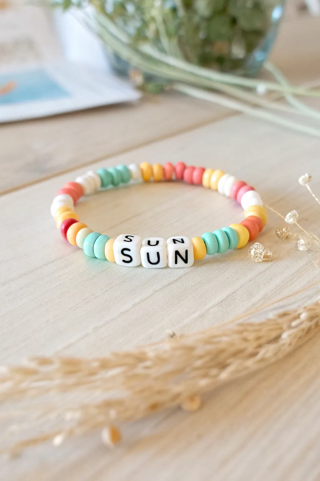 Preppy summer bracelet with pastel clay heishi beads and bold letter beads in warm sunlight