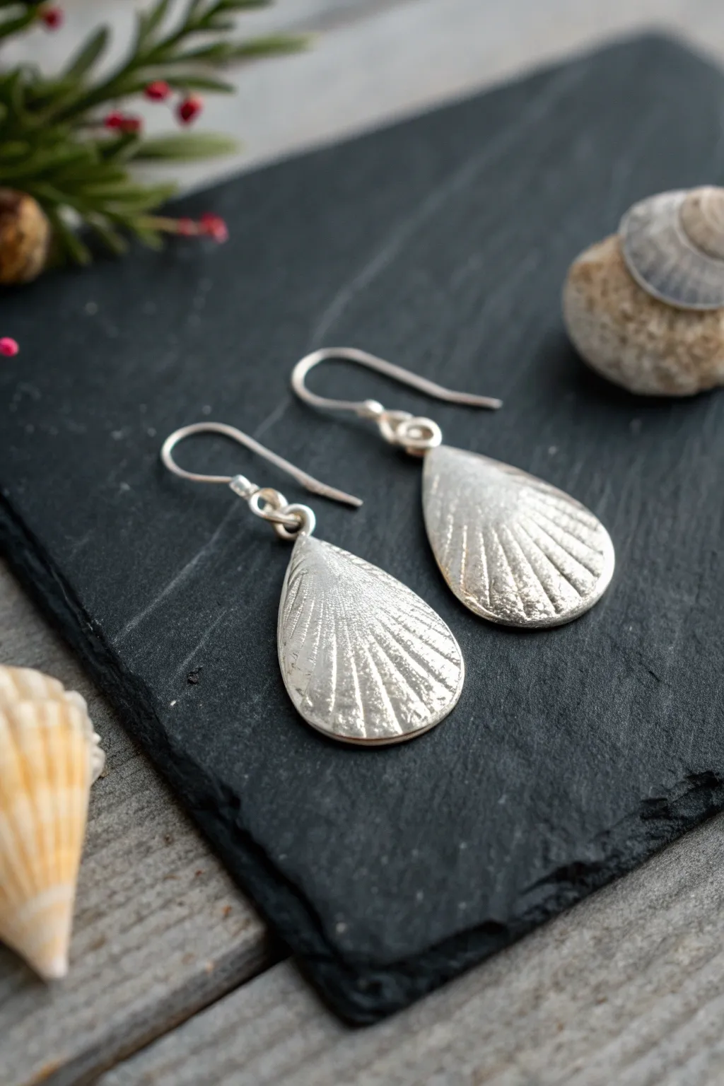 Shell-imprint silver clay drop earrings with soft patina, styled simply on matte charcoal.