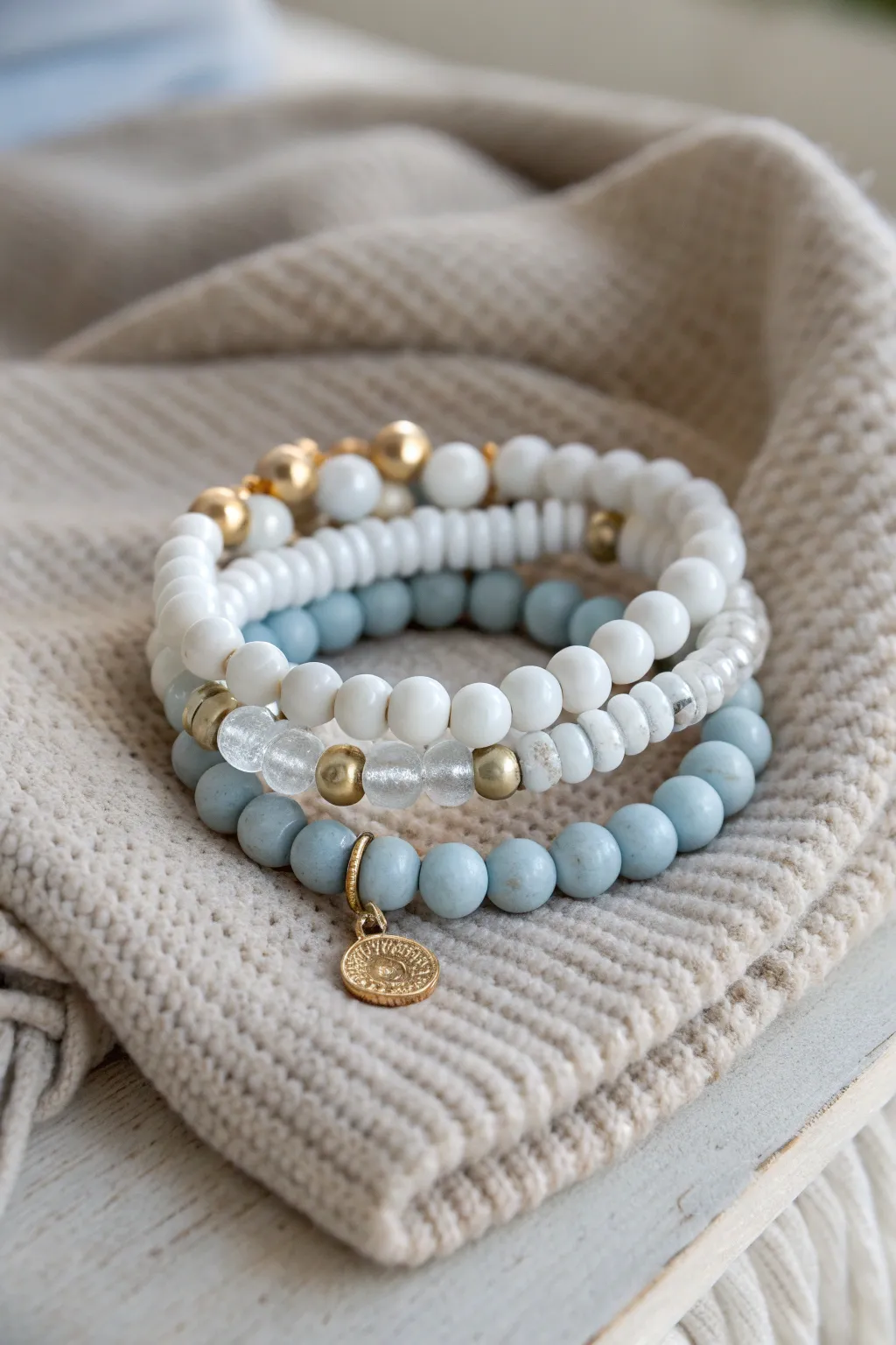 Classic winter clay bead bracelet stack in soft whites and icy blue with simple metallic accents