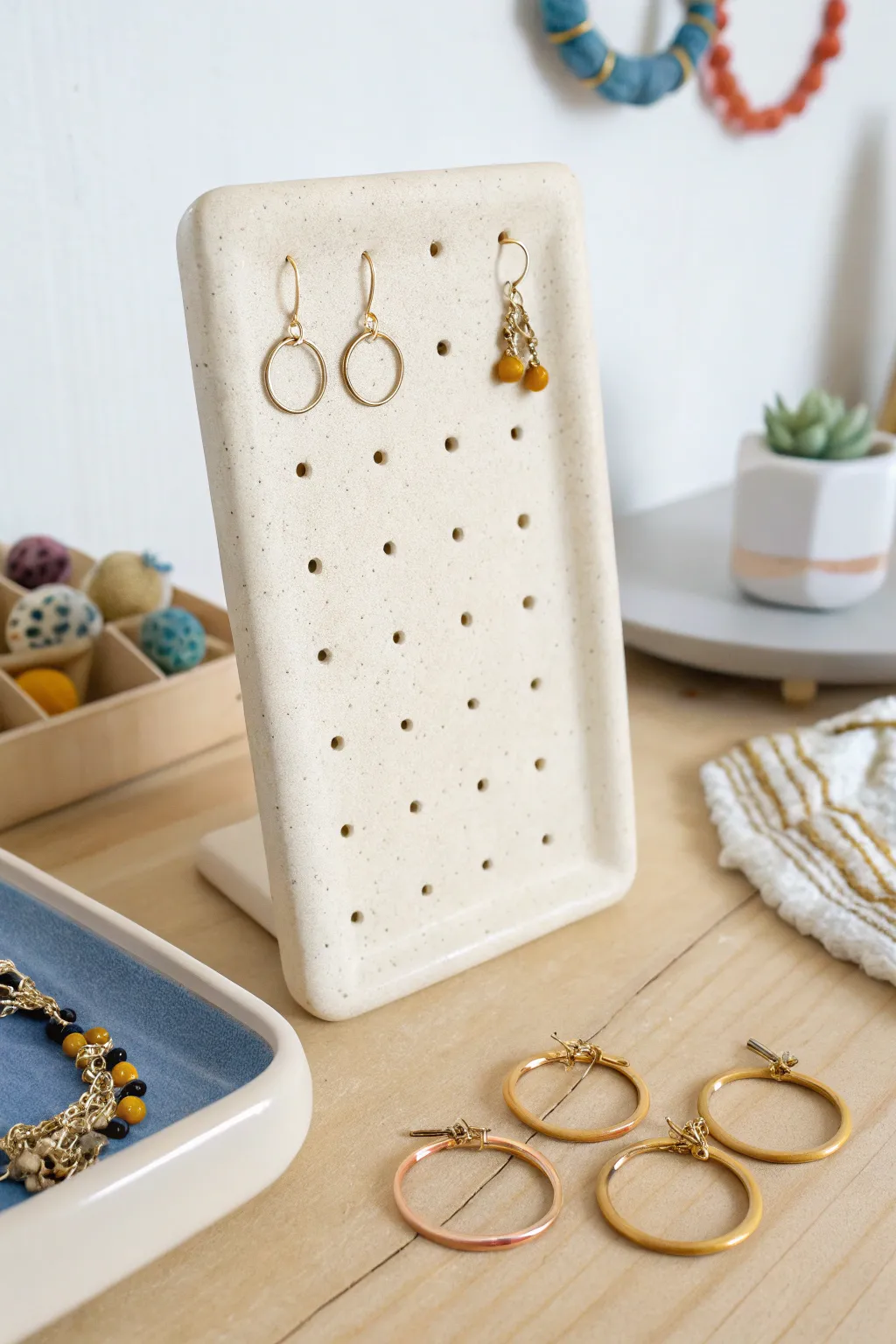 Minimal air-dry clay earring display slab with neat holes, showcasing bold hoops and studs.
