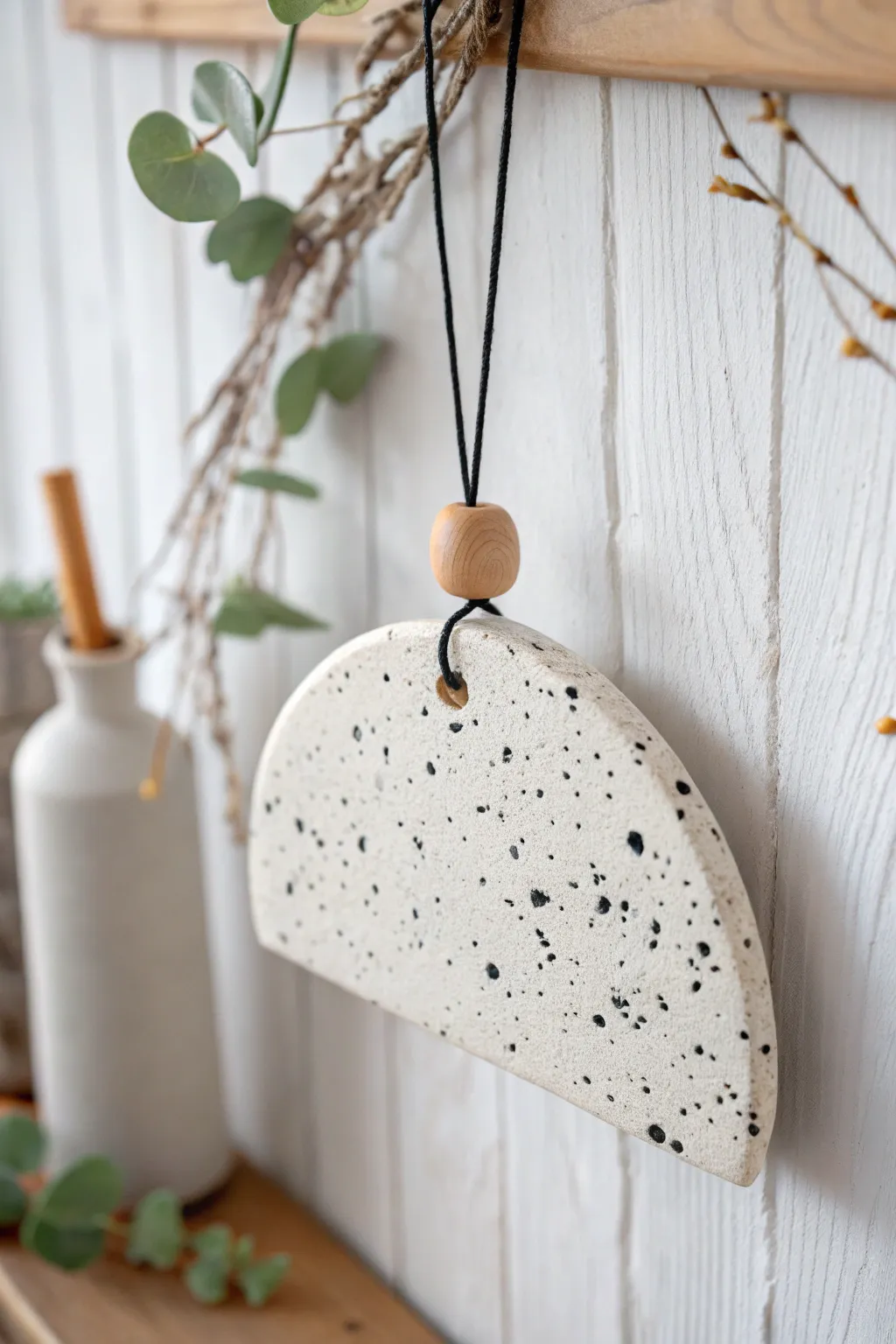 Minimal speckled stone-look air dry clay hanging with bold black cord on a light wall