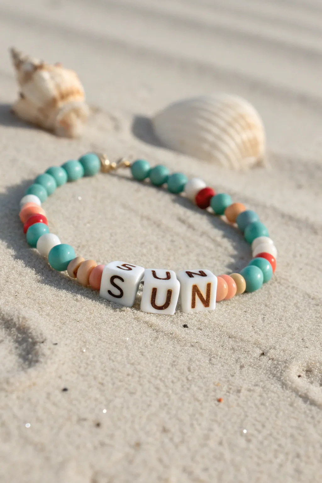 Aqua and sand clay bead bracelet with SUN letter beads, styled on beach sand for summer vibes