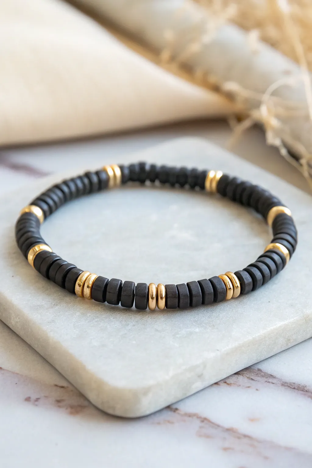 Minimal dark disc bracelet with tiny metallic spacers, a modern boy-friendly clay bead look.