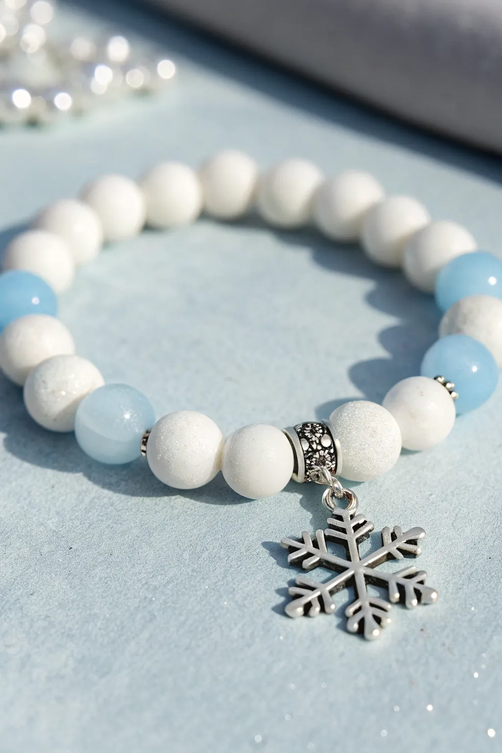 Snow Day palette bracelet: white clay beads, icy blue accents, and a simple snowflake charm