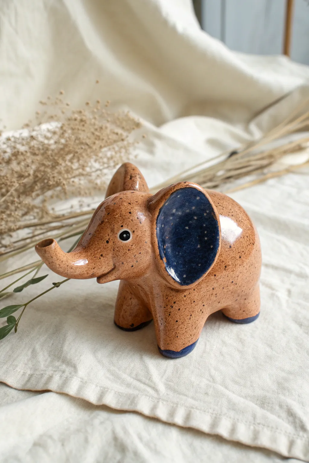 Minimalist clay elephant with oversized ears in bold terracotta and cobalt, sweet and handcrafted.