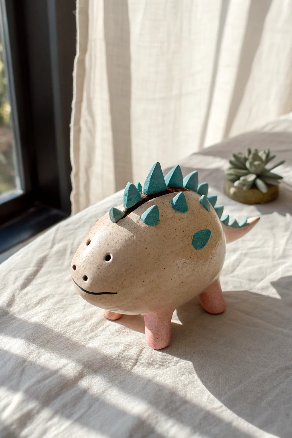 Chubby dinosaur clay bank with hidden coin slot and playful spikes in bold modern colors.