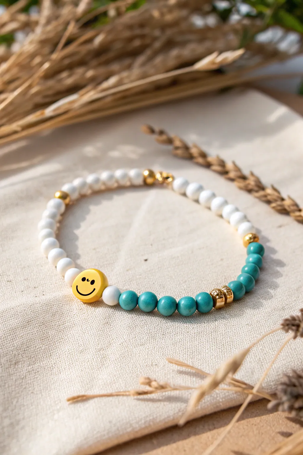 Color-blocked clay bead bracelet with gold spacers and a bright smiley face centerpiece.
