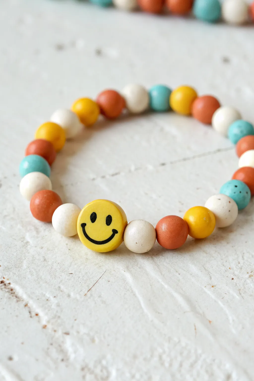 Smiley charm in the center of sunny clay discs, framed by bold spacers for instant joy