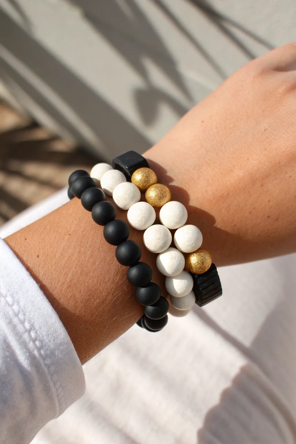 High-contrast black and white clay bead bracelet stack with a subtle metallic shimmer.