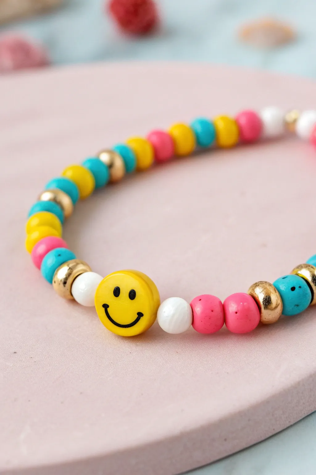 Smiley centerpiece, bright heishi clay beads and gold spacers on soft pink for happy boho minimal vibes.