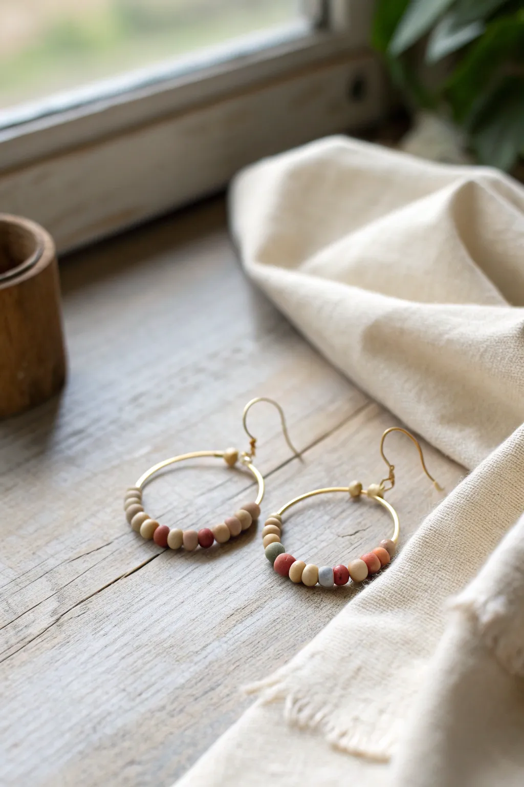 Earthy neutral heishi clay bead hoops in tan, cream, rust, and olive for effortless daily style.