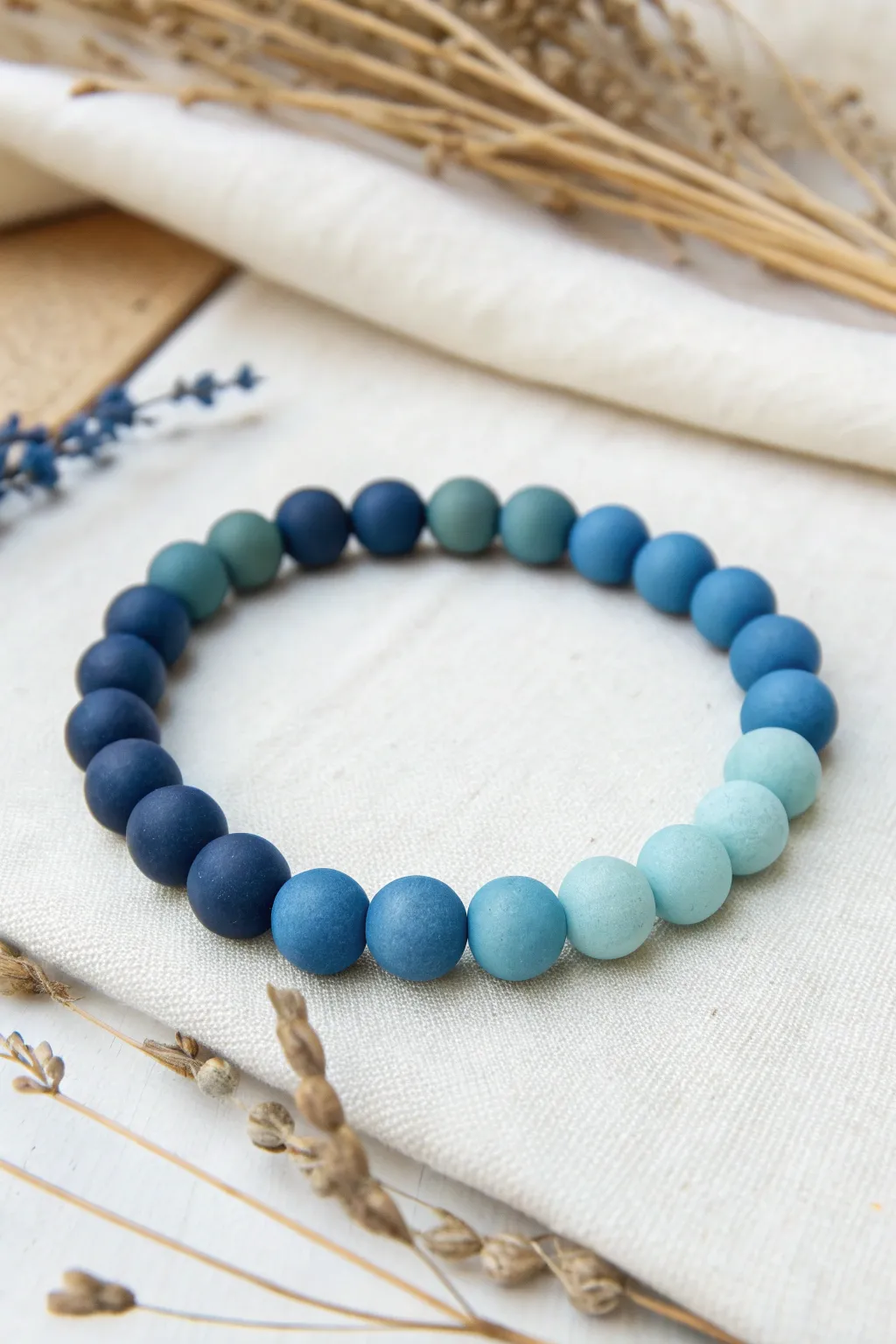 Soft ombre polymer clay bead bracelet in navy to sky blue, minimalist flat lay with bold contrast