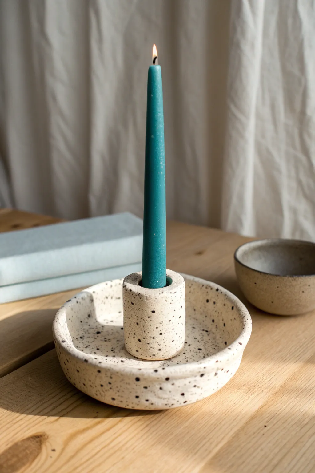 Speckled clay candle holder with a bold taper, minimalist studio styling and handmade charm.