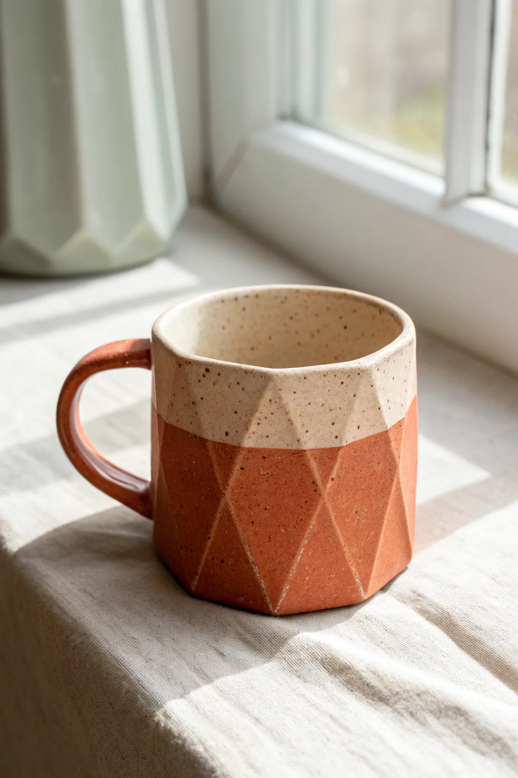 Faceted ceramic mug with crisp planes, bold terracotta glaze, and clean Scandinavian contrast.