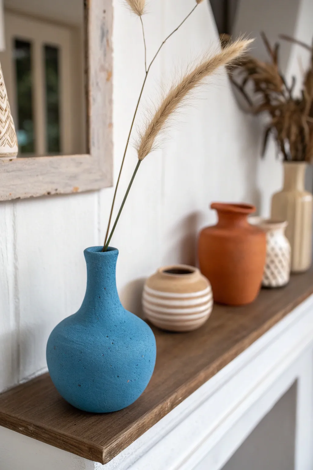 Minimal air-dry clay bud vase on a shelf, bold color contrast and a single dried stem