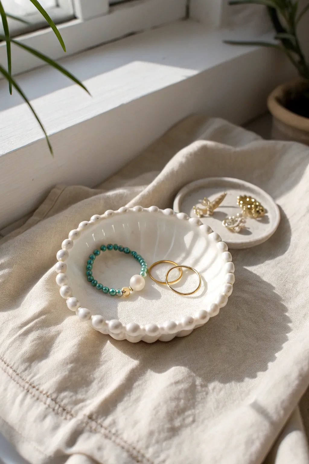 Matte white beaded-edge dish styled with gold and turquoise jewelry on linen, minimal boho charm