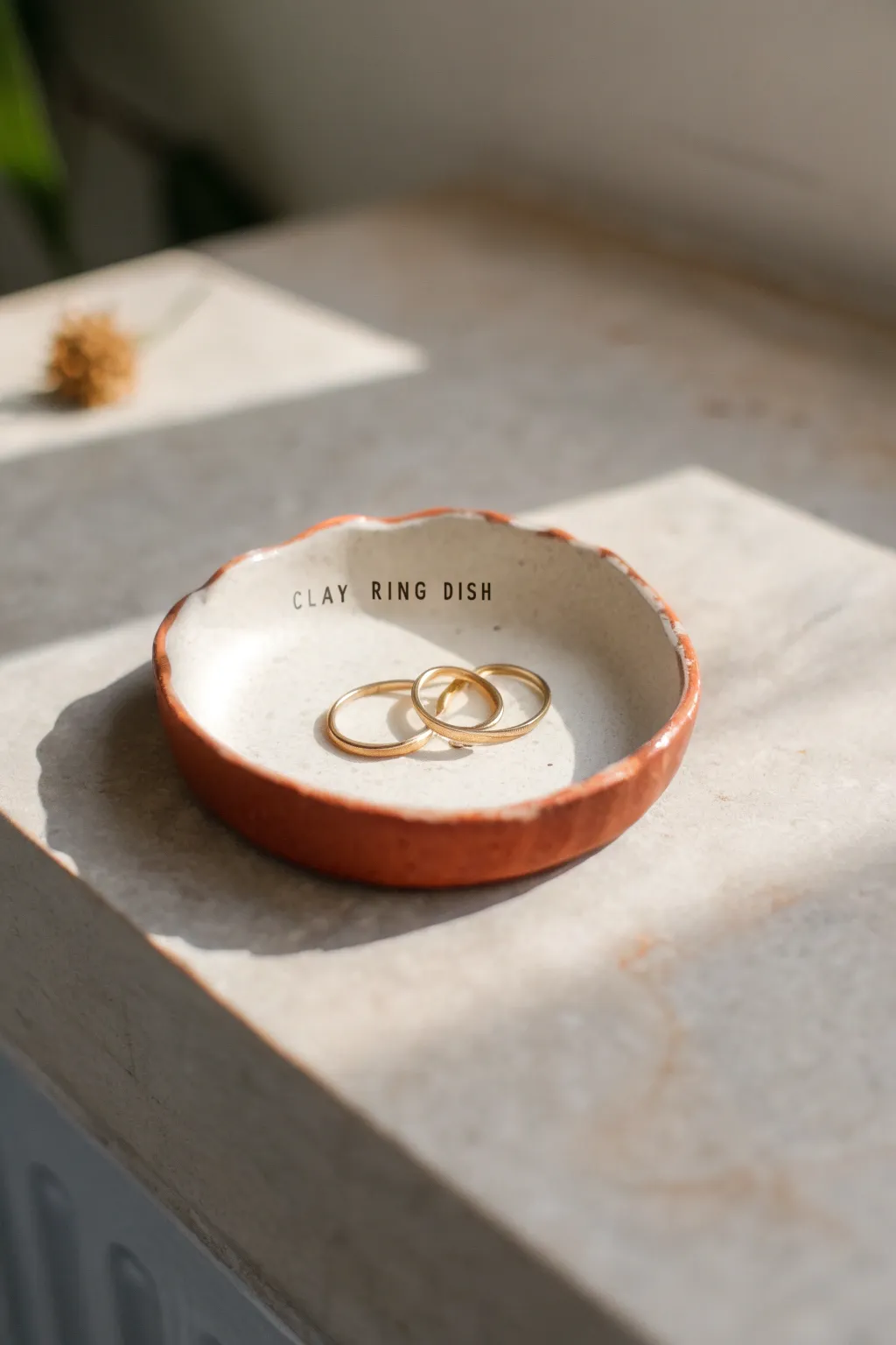 Bold terracotta stamped name ring dish with a few gold rings, minimalist and beautifully handmade.