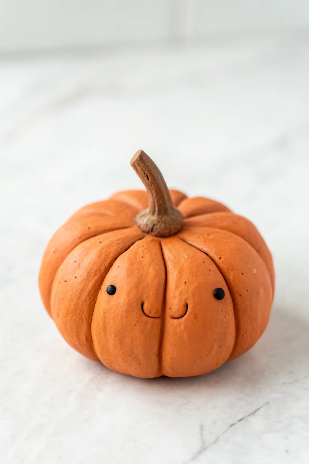 Easy clay pumpkin with simple grooves and dot eyes, a cute minimalist fall figure anyone can make.