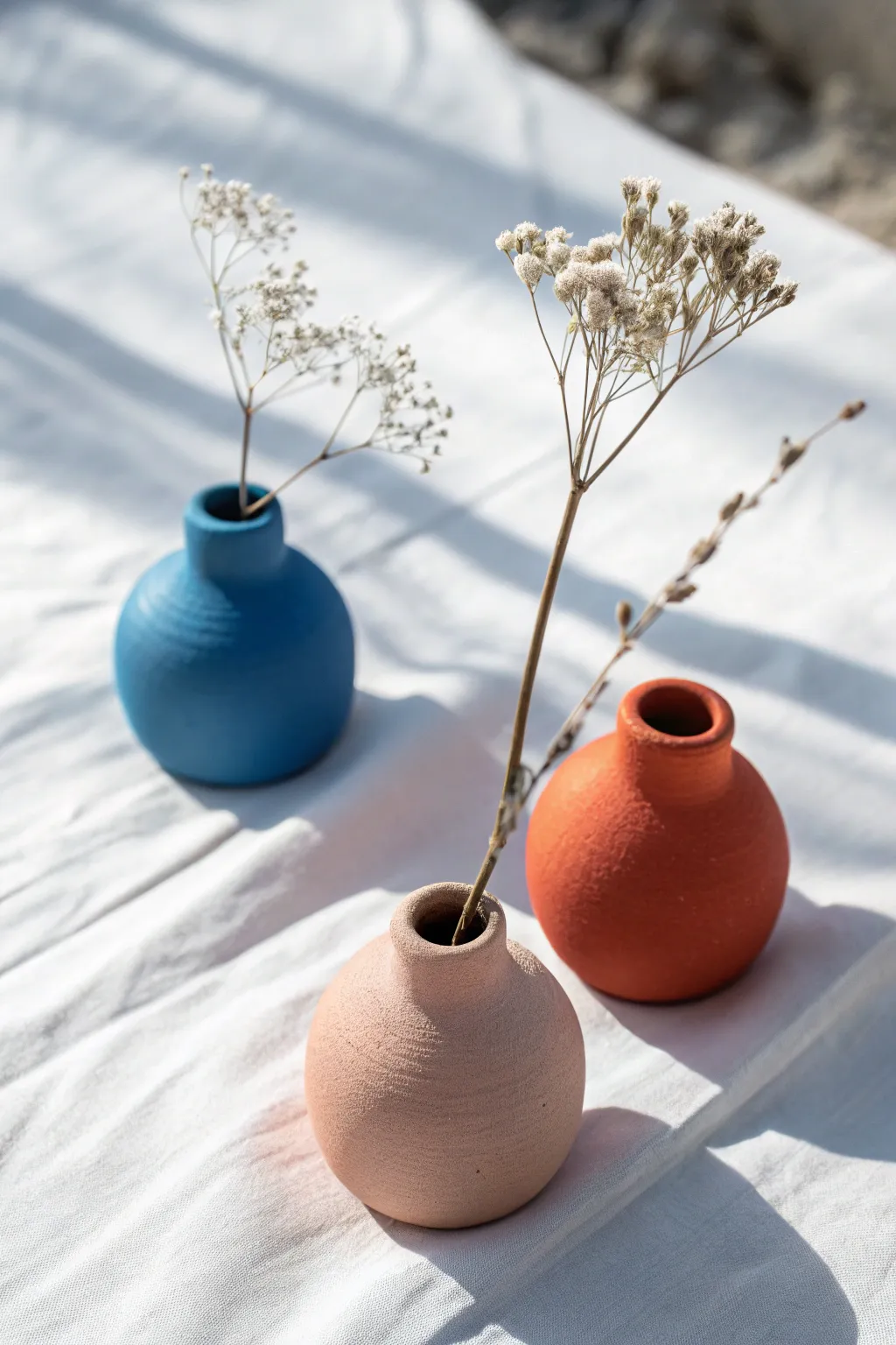 Tiny clay vase magnets with dried mini blooms, bold color pops on a clean Scandinavian backdrop.