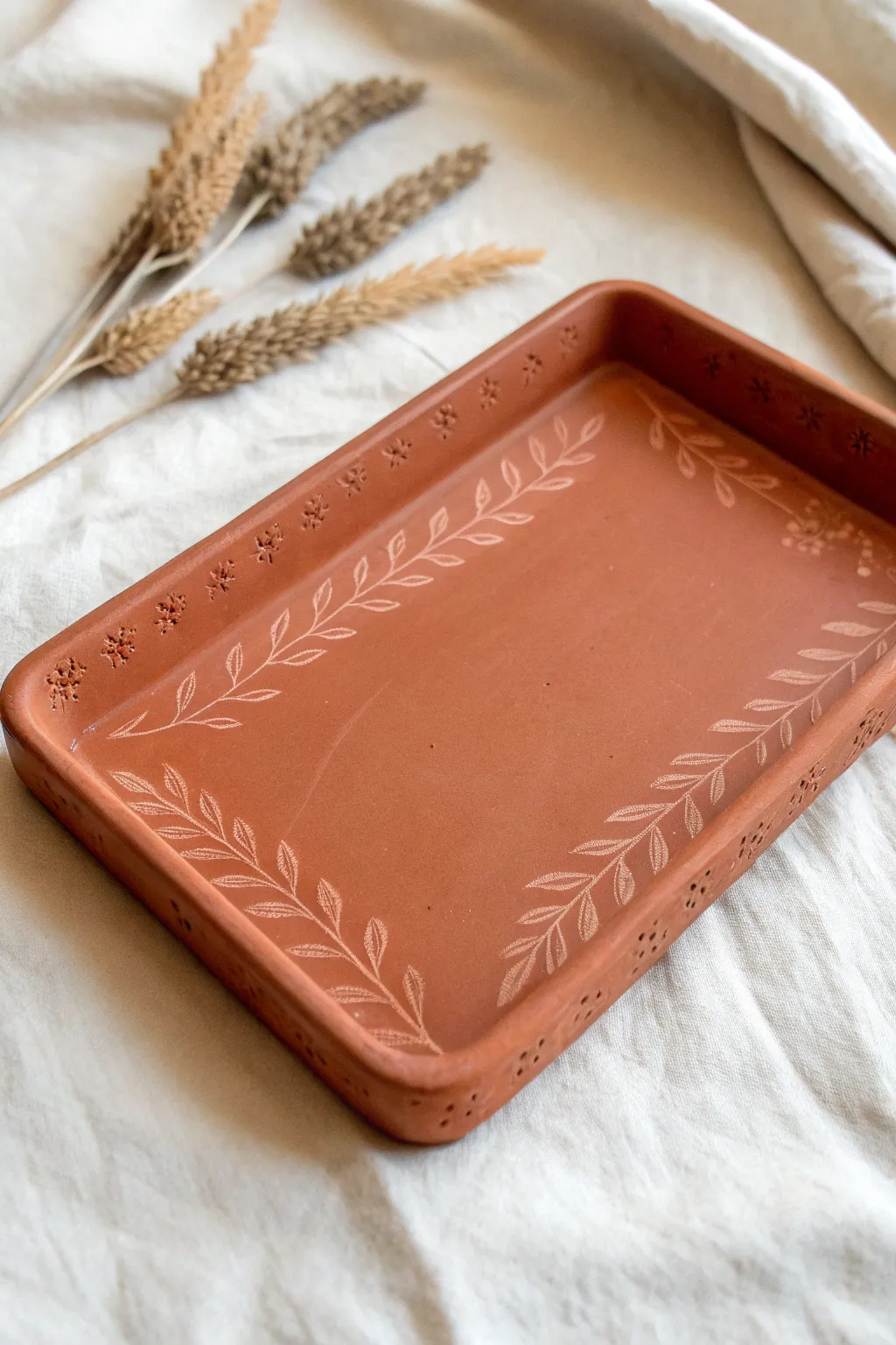 Minimal terracotta rolling tray with delicate botanical imprints framing a smooth center