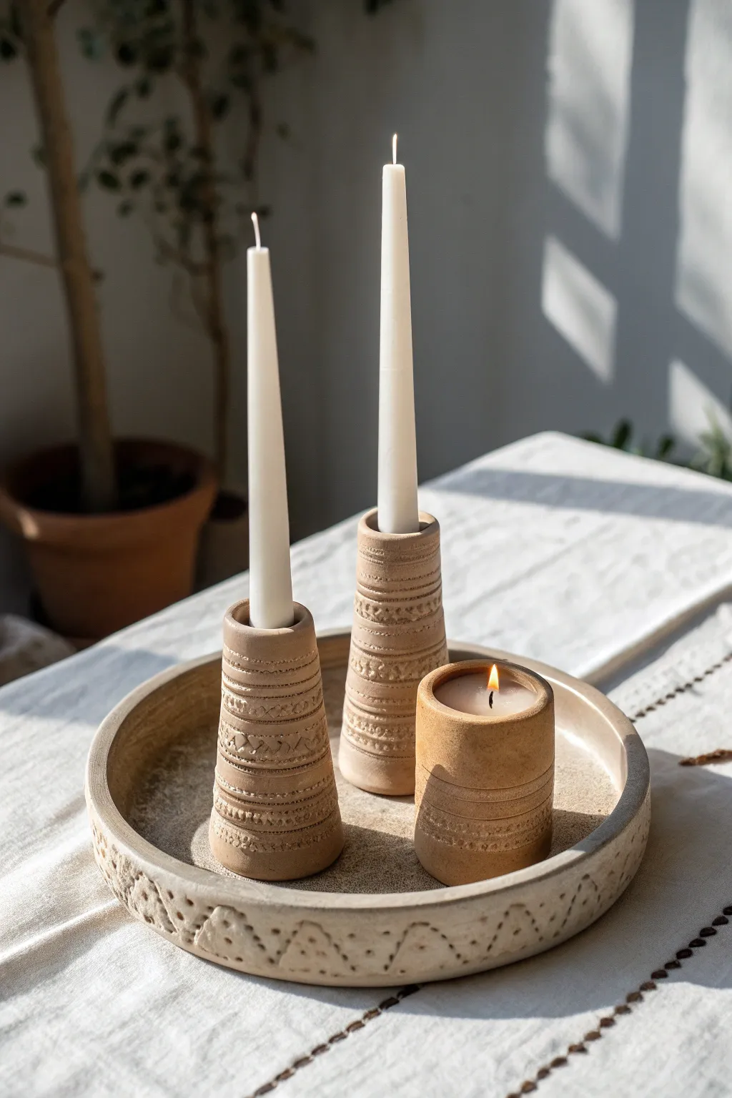 Three matte clay candle holders in mixed heights, styled simply for a calm, modern glow