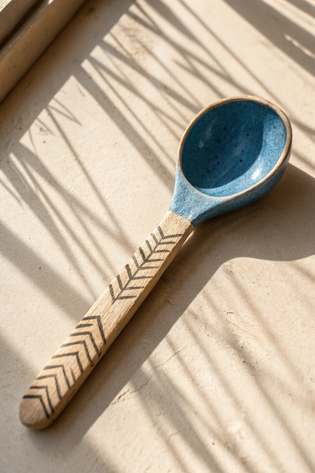 Minimal clay spoon with carved line handle in bold glaze, styled simply on a pale surface.