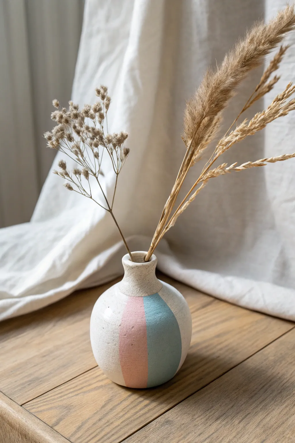 Mini pastel clay bud vase with a single dried bloom, minimalist styling for tiny flowers.