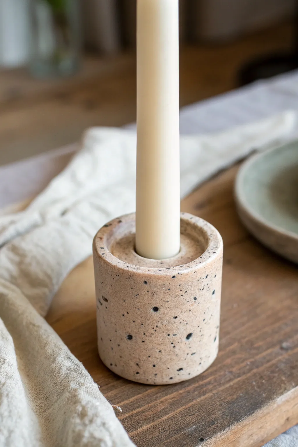 Speckled stone-effect taper holder in light clay, minimalist lines and tactile handmade texture.