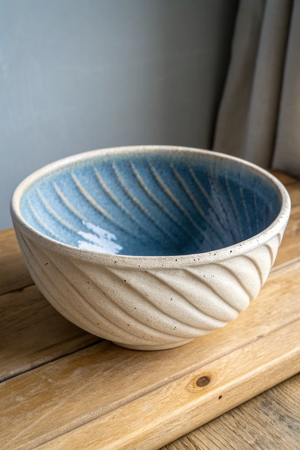 Handcrafted drape bowl on a rustic coil foot ring, minimalist curves with a bold blue interior.