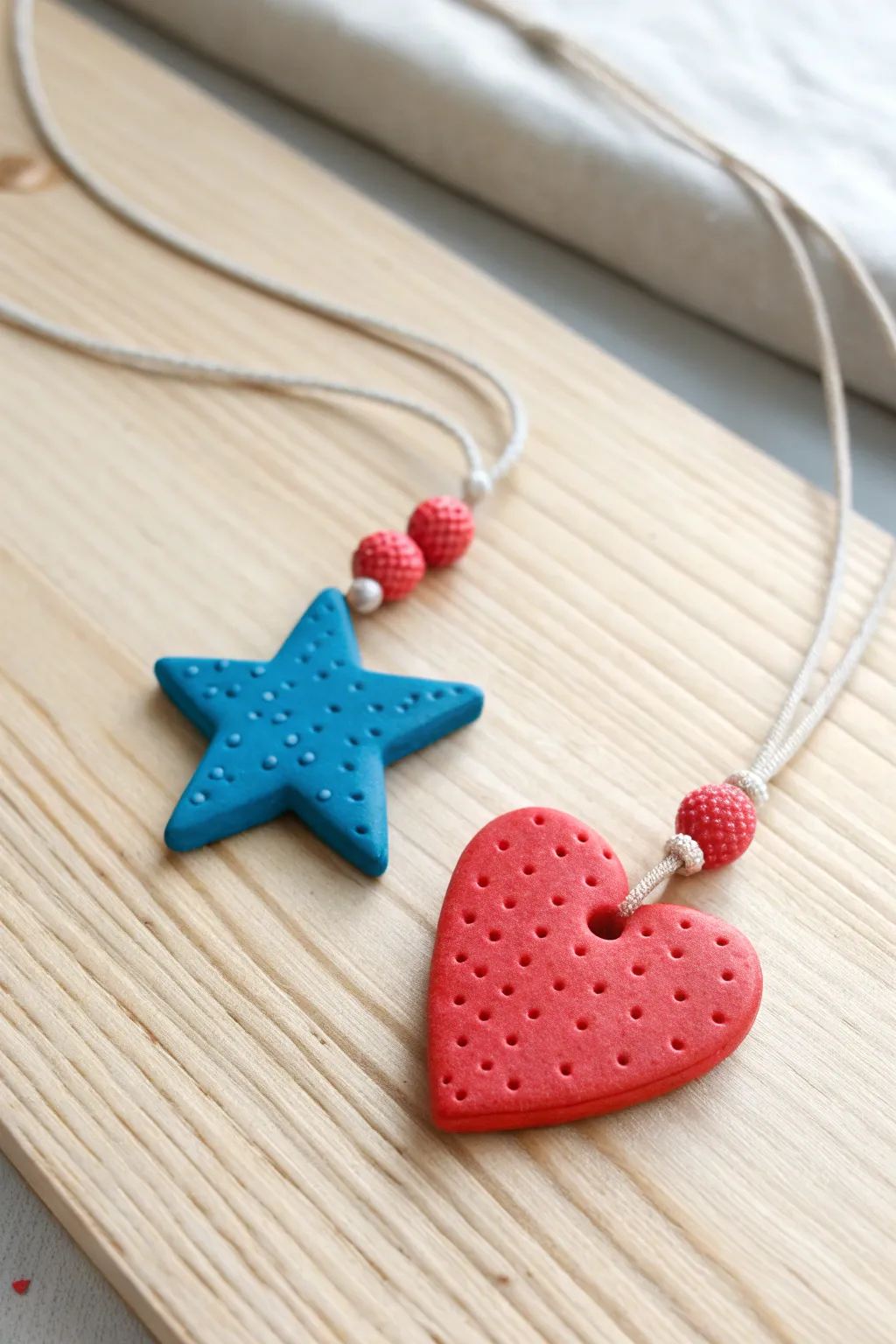 Chunky star and heart polymer clay pendants in bold colors, a simple kids necklace on wood.