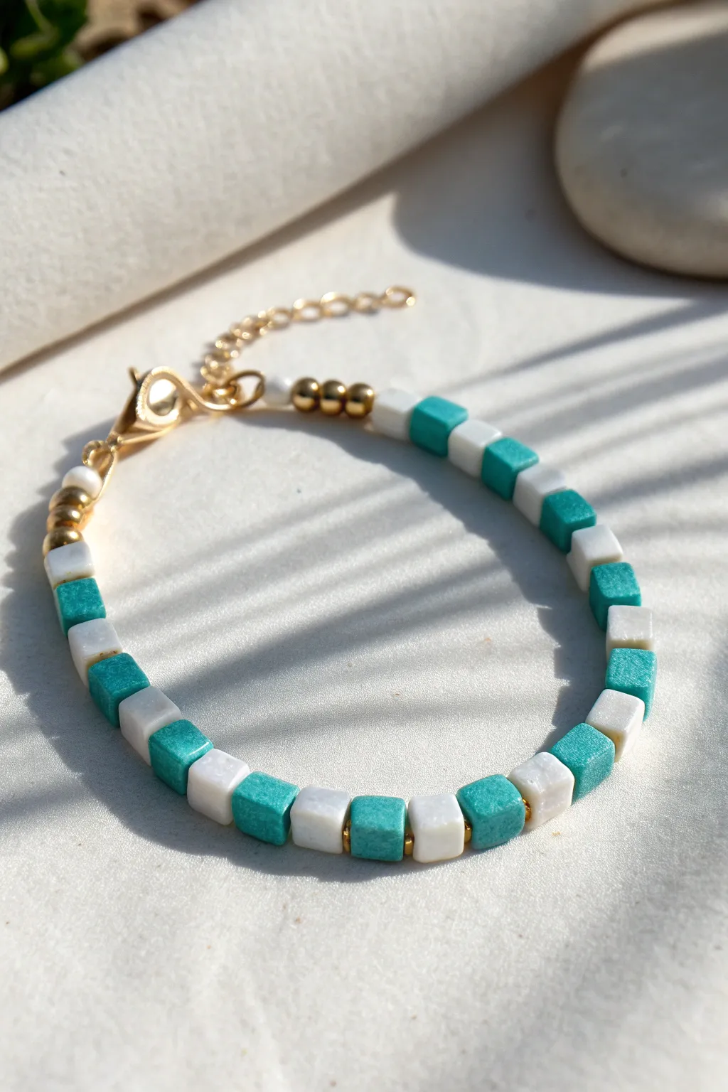 Teal and white clay bead bracelet in a clean checkerboard pattern, bold yet minimal.