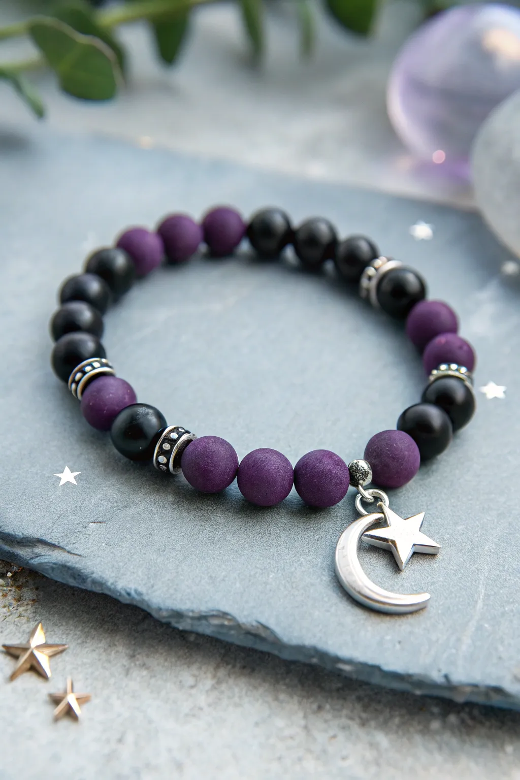 Witchy black and purple clay bead bracelet with moon charm and star beads on soft gray