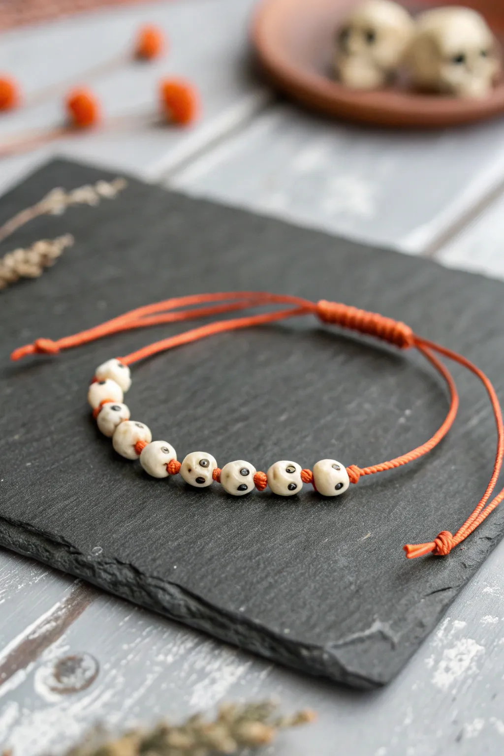 Mini skull bead bracelet in off white clay on burnt orange cord, minimal boho Halloween style